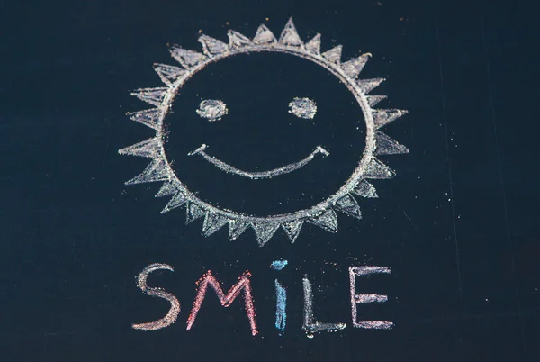 Smile icon painted. Smiling emoticon. SMILE message word on a wooden desk.