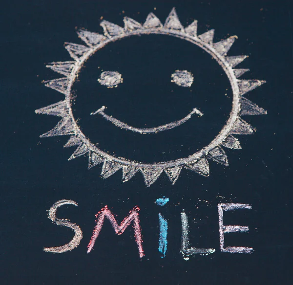 Smile icon painted. Smiling emoticon. SMILE message word on a wooden desk.