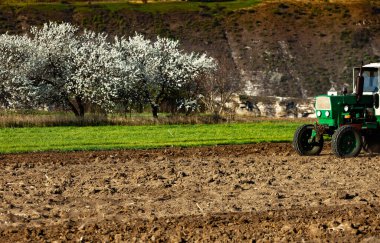 Traktördeki çiftçi araziyi hazırlıyor. Tarım arazilerinde tarım işleri. Bir traktörün üzerinde tarla sürme işi. Moldova, Avrupa 'da bir çiftçi tarlasında traktör.