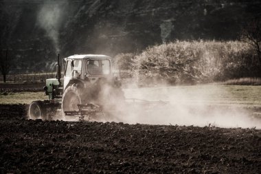 Traktördeki çiftçi araziyi hazırlıyor. Tarım arazilerinde tarım işleri. Bir traktörün üzerinde tarla sürme işi. Moldova, Avrupa 'da bir çiftçi tarlasında traktör.