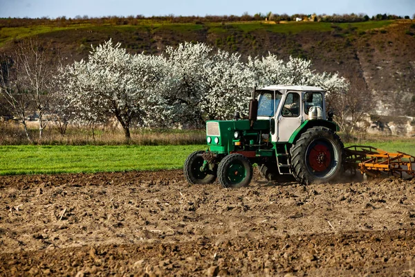 Farmer in tractor preparing land. Agricultural works at farmlands. agricultural work plowing land on a  tractor. Tractor on a farmer field in Moldova, Europe.