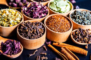 Tahta kasede çeşitli kurutulmuş çay yaprakları. Kurutulmuş bitki çayı yaprakları kapanıyor. Sağlıklı çay yapmak için farklı bitkiler ve çiçekler..