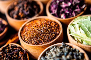 Tahta kasede çeşitli kurutulmuş çay yaprakları. Kurutulmuş bitki çayı yaprakları kapanıyor. Sağlıklı çay yapmak için farklı bitkiler ve çiçekler..