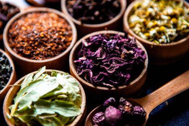 Tahta kasede çeşitli kurutulmuş çay yaprakları. Kurutulmuş bitki çayı yaprakları kapanıyor. Sağlıklı çay yapmak için farklı bitkiler ve çiçekler..