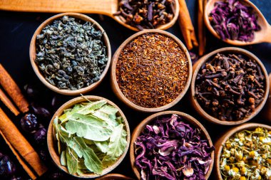 Tahta kasede çeşitli kurutulmuş çay yaprakları. Kurutulmuş bitki çayı yaprakları kapanıyor. Sağlıklı çay yapmak için farklı bitkiler ve çiçekler..