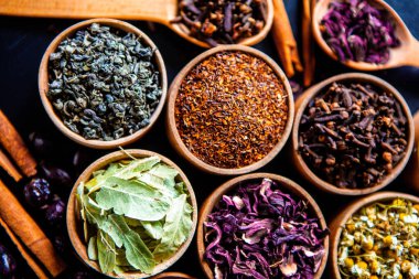 Tahta kasede çeşitli kurutulmuş çay yaprakları. Kurutulmuş bitki çayı yaprakları kapanıyor. Sağlıklı çay yapmak için farklı bitkiler ve çiçekler..