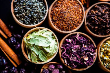 Tahta kasede çeşitli kurutulmuş çay yaprakları. Kurutulmuş bitki çayı yaprakları kapanıyor. Sağlıklı çay yapmak için farklı bitkiler ve çiçekler..