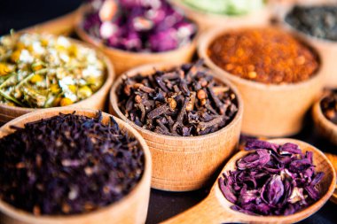 Tahta kasede çeşitli kurutulmuş çay yaprakları. Kurutulmuş bitki çayı yaprakları kapanıyor. Sağlıklı çay yapmak için farklı bitkiler ve çiçekler..