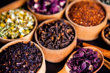 Tahta kasede çeşitli kurutulmuş çay yaprakları. Kurutulmuş bitki çayı yaprakları kapanıyor. Sağlıklı çay yapmak için farklı bitkiler ve çiçekler..