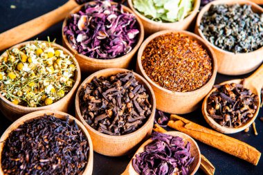 Tahta kasede çeşitli kurutulmuş çay yaprakları. Kurutulmuş bitki çayı yaprakları kapanıyor. Sağlıklı çay yapmak için farklı bitkiler ve çiçekler..