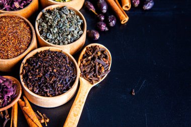 Tahta kasede çeşitli kurutulmuş çay yaprakları. Kurutulmuş bitki çayı yaprakları kapanıyor. Sağlıklı çay yapmak için farklı bitkiler ve çiçekler..