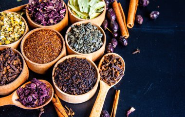 Tahta kasede çeşitli kurutulmuş çay yaprakları. Kurutulmuş bitki çayı yaprakları kapanıyor. Sağlıklı çay yapmak için farklı bitkiler ve çiçekler..