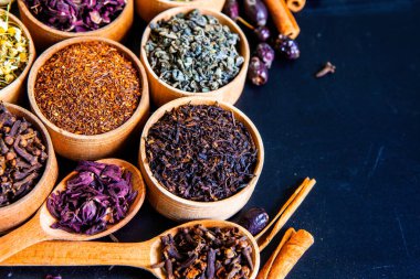 Tahta kasede çeşitli kurutulmuş çay yaprakları. Kurutulmuş bitki çayı yaprakları kapanıyor. Sağlıklı çay yapmak için farklı bitkiler ve çiçekler..