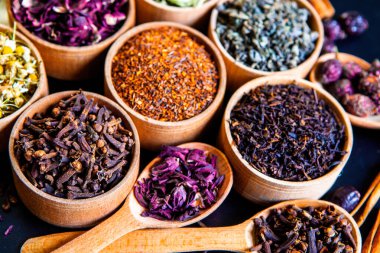 Tahta kasede çeşitli kurutulmuş çay yaprakları. Kurutulmuş bitki çayı yaprakları kapanıyor. Sağlıklı çay yapmak için farklı bitkiler ve çiçekler..