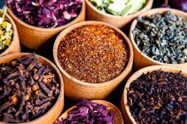 Tahta kasede çeşitli kurutulmuş çay yaprakları. Kurutulmuş bitki çayı yaprakları kapanıyor. Sağlıklı çay yapmak için farklı bitkiler ve çiçekler..