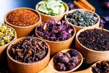 Tahta kasede çeşitli kurutulmuş çay yaprakları. Kurutulmuş bitki çayı yaprakları kapanıyor. Sağlıklı çay yapmak için farklı bitkiler ve çiçekler..