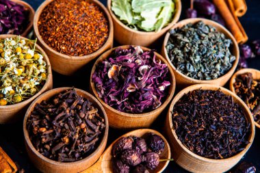 Tahta kasede çeşitli kurutulmuş çay yaprakları. Kurutulmuş bitki çayı yaprakları kapanıyor. Sağlıklı çay yapmak için farklı bitkiler ve çiçekler..