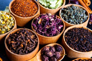 Tahta kasede çeşitli kurutulmuş çay yaprakları. Kurutulmuş bitki çayı yaprakları kapanıyor. Sağlıklı çay yapmak için farklı bitkiler ve çiçekler..