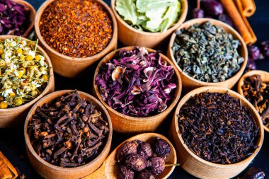 Tahta kasede çeşitli kurutulmuş çay yaprakları. Kurutulmuş bitki çayı yaprakları kapanıyor. Sağlıklı çay yapmak için farklı bitkiler ve çiçekler..