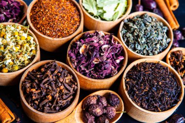 Tahta kasede çeşitli kurutulmuş çay yaprakları. Kurutulmuş bitki çayı yaprakları kapanıyor. Sağlıklı çay yapmak için farklı bitkiler ve çiçekler..