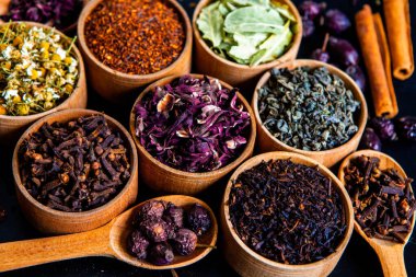 Tahta kasede çeşitli kurutulmuş çay yaprakları. Kurutulmuş bitki çayı yaprakları kapanıyor. Sağlıklı çay yapmak için farklı bitkiler ve çiçekler..