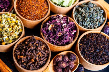 Tahta kasede çeşitli kurutulmuş çay yaprakları. Kurutulmuş bitki çayı yaprakları kapanıyor. Sağlıklı çay yapmak için farklı bitkiler ve çiçekler..