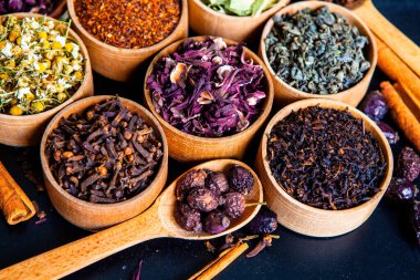 Tahta kasede çeşitli kurutulmuş çay yaprakları. Kurutulmuş bitki çayı yaprakları kapanıyor. Sağlıklı çay yapmak için farklı bitkiler ve çiçekler..