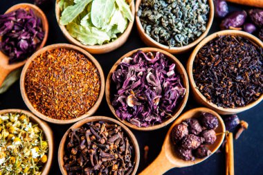 Tahta kasede çeşitli kurutulmuş çay yaprakları. Kurutulmuş bitki çayı yaprakları kapanıyor. Sağlıklı çay yapmak için farklı bitkiler ve çiçekler..