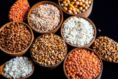 Bir kase mısır gevreği. Çeşitli doğal tahıl ve tahıllar. Siyah arka planda kaselerdeki farklı Groats tipleri. Sağlıklı besin.