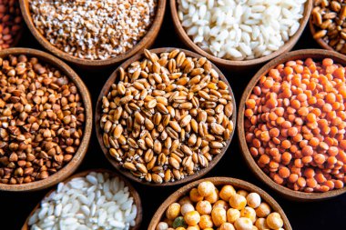 Bir kase mısır gevreği. Çeşitli doğal tahıl ve tahıllar. Siyah arka planda kaselerdeki farklı Groats tipleri. Sağlıklı besin.