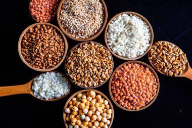 Bir kase mısır gevreği. Çeşitli doğal tahıl ve tahıllar. Siyah arka planda kaselerdeki farklı Groats tipleri. Sağlıklı besin.