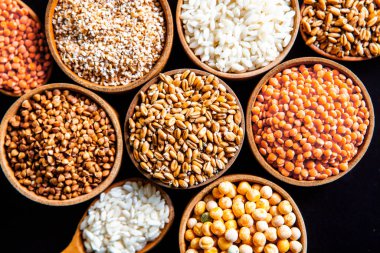 Bir kase mısır gevreği. Çeşitli doğal tahıl ve tahıllar. Siyah arka planda kaselerdeki farklı Groats tipleri. Sağlıklı besin.