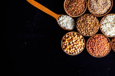 Bir kase mısır gevreği. Çeşitli doğal tahıl ve tahıllar. Siyah arka planda kaselerdeki farklı Groats tipleri. Sağlıklı besin.