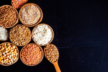 Bir kase mısır gevreği. Çeşitli doğal tahıl ve tahıllar. Siyah arka planda kaselerdeki farklı Groats tipleri. Sağlıklı besin.