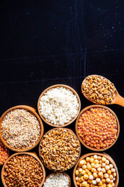 Bir kase mısır gevreği. Çeşitli doğal tahıl ve tahıllar. Siyah arka planda kaselerdeki farklı Groats tipleri. Sağlıklı besin.