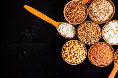 Bir kase mısır gevreği. Çeşitli doğal tahıl ve tahıllar. Siyah arka planda kaselerdeki farklı Groats tipleri. Sağlıklı besin.