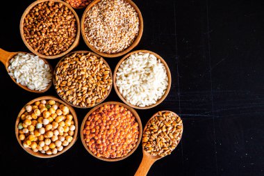 Bir kase mısır gevreği. Çeşitli doğal tahıl ve tahıllar. Siyah arka planda kaselerdeki farklı Groats tipleri. Sağlıklı besin.