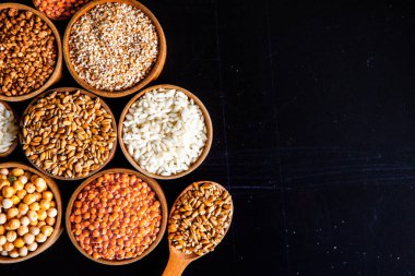 Bir kase mısır gevreği. Çeşitli doğal tahıl ve tahıllar. Siyah arka planda kaselerdeki farklı Groats tipleri. Sağlıklı besin.