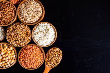 Bir kase mısır gevreği. Çeşitli doğal tahıl ve tahıllar. Siyah arka planda kaselerdeki farklı Groats tipleri. Sağlıklı besin.