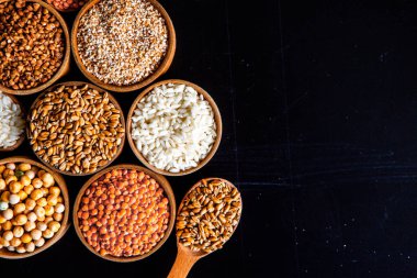 Bir kase mısır gevreği. Çeşitli doğal tahıl ve tahıllar. Siyah arka planda kaselerdeki farklı Groats tipleri. Sağlıklı besin.