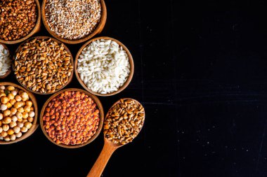 Bir kase mısır gevreği. Çeşitli doğal tahıl ve tahıllar. Siyah arka planda kaselerdeki farklı Groats tipleri. Sağlıklı besin.