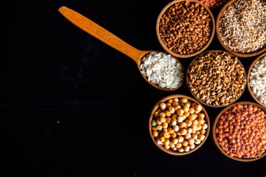 Bir kase mısır gevreği. Çeşitli doğal tahıl ve tahıllar. Siyah arka planda kaselerdeki farklı Groats tipleri. Sağlıklı besin.