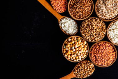 Bir kase mısır gevreği. Çeşitli doğal tahıl ve tahıllar. Siyah arka planda kaselerdeki farklı Groats tipleri. Sağlıklı besin.