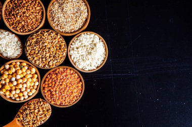 Bir kase mısır gevreği. Çeşitli doğal tahıl ve tahıllar. Siyah arka planda kaselerdeki farklı Groats tipleri. Sağlıklı besin.