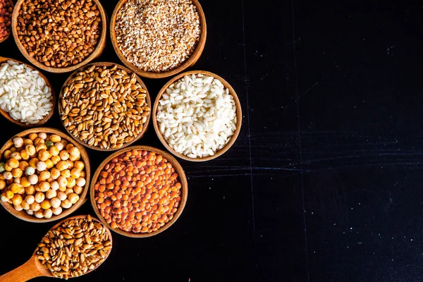 様々なシリアルのボウル 天然穀物や穀物の様々な種類 黒い背景にボウルにさまざまな種類のグラット 健康的な栄養食品 — ストック写真