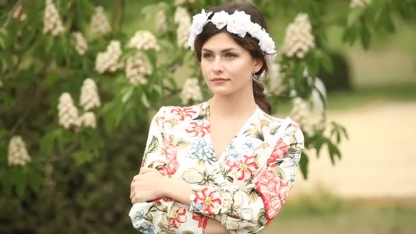 風に動く髪を持つ女性の肖像画 夏の緑の公園で若い美しいロシアのブルネットの女の子のクローズアップ肖像画 ヨーロッパの白人女性のドレス — ストック動画