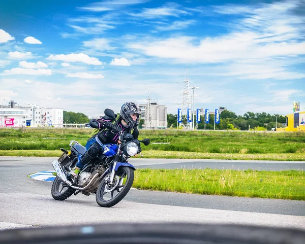 Ulyanovsk, Rússia - 10 de junho de 2017. Menina em uma corrida jaqueta preta em uma motocicleta azul em uma pista de esportes . — Fotografia de Stock