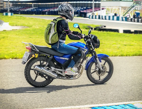 Oulianovsk, Russie - 10 juin 2017. Fille dans une veste noire course sur une moto bleue sur une piste de sport . — Photo