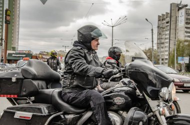 Ulyanovsk, Rusya - 03 Mayıs 2019: Bir adam Harley Davidson motosikletini bir konvoy motosikletle şehir caddesi boyunca sürüyor.