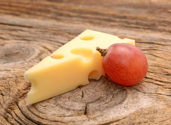 Emmentaler Käse mit Trauben auf Holzgrund — Stockfoto